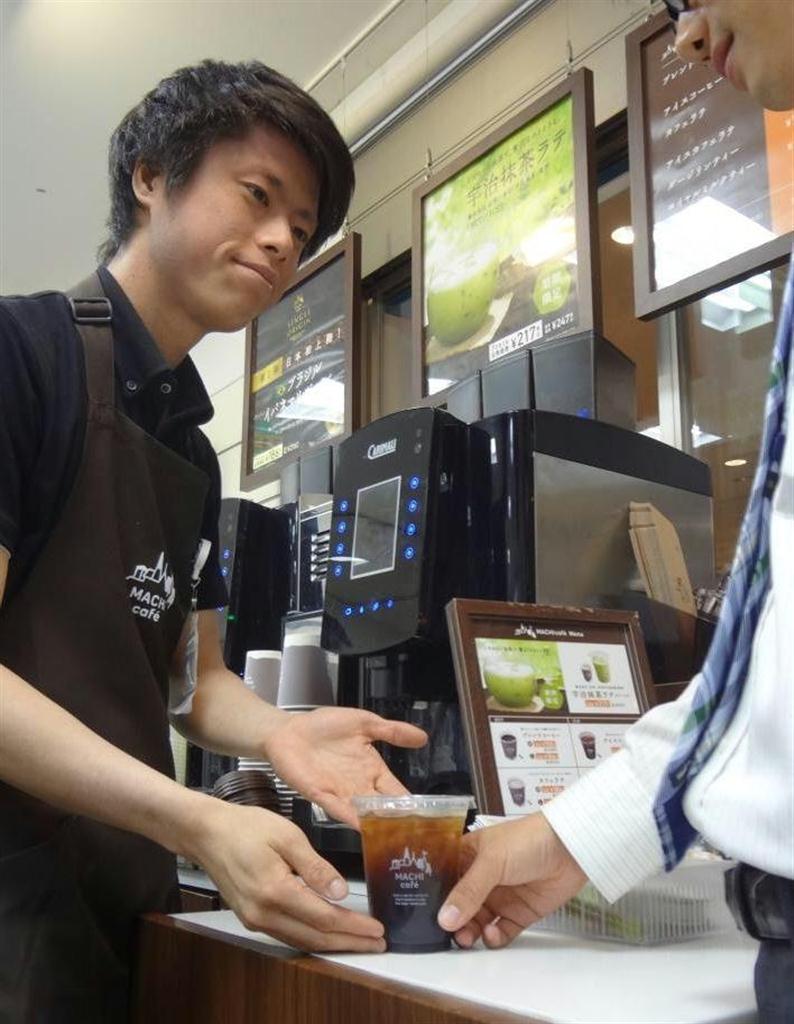 カウンターでいれたてコーヒーを手渡すローソンの店員＝東京都品川区（平尾孝撮影）