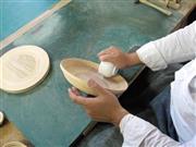 バウムクーヘンのようになった平面の巻き板を、湯呑みを使って立体に形を作り上げていく＝２０１４年９月１３日（ブナコ提供）