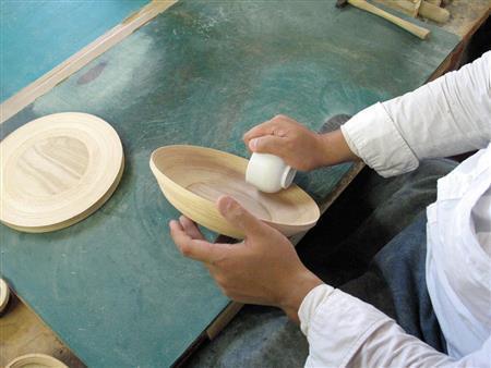 バウムクーヘンのようになった平面の巻き板を、湯呑みを使って立体に形を作り上げていく＝２０１４年９月１３日（ブナコ提供）