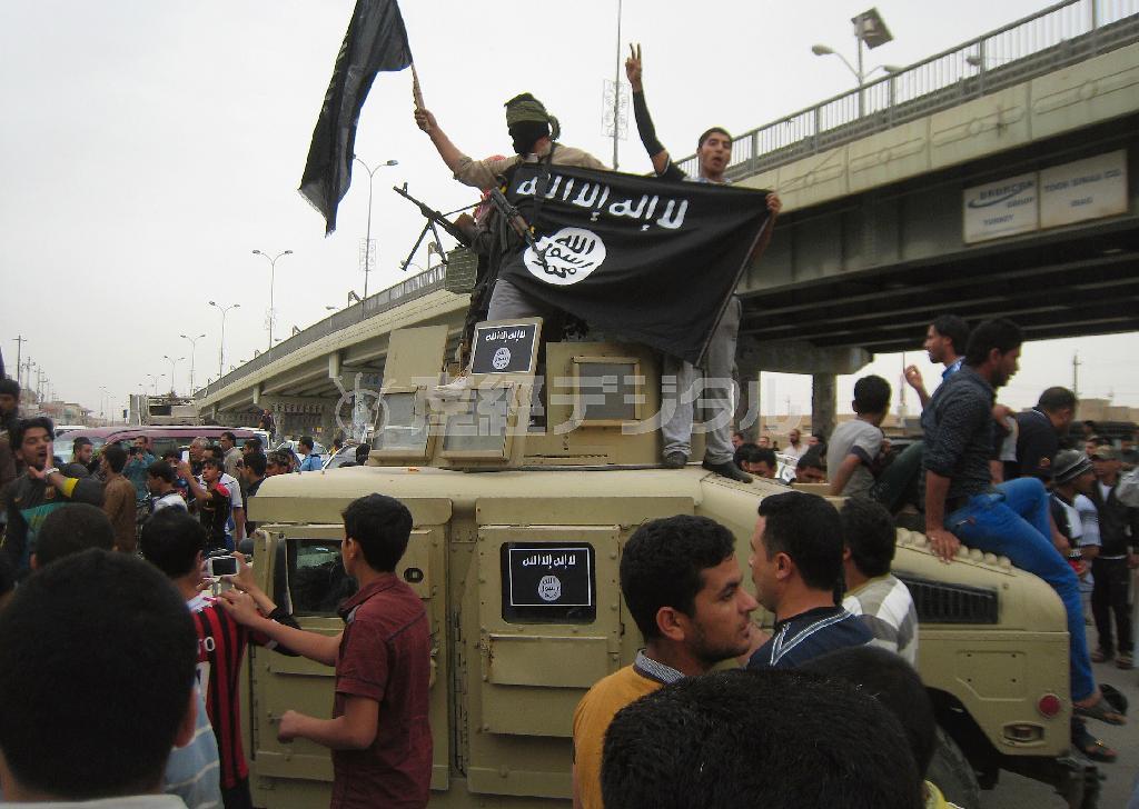 イラクのファルージャで装甲車に乗り、“国旗”を振るイスラム国の戦闘員＝２０１４年３月３０日（ＡＰ）