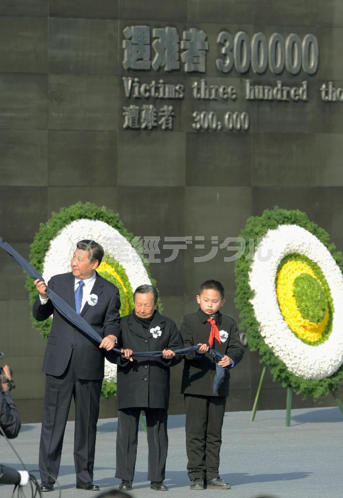 ２０１４年１２月１３日、南京大虐殺記念館で開かれた追悼式典に出席し、モニュメントの除幕を行う習近平国家主席（左）。背後の壁には「遭難者３０万人」と記されている＝中国・江蘇省南京市（共同）