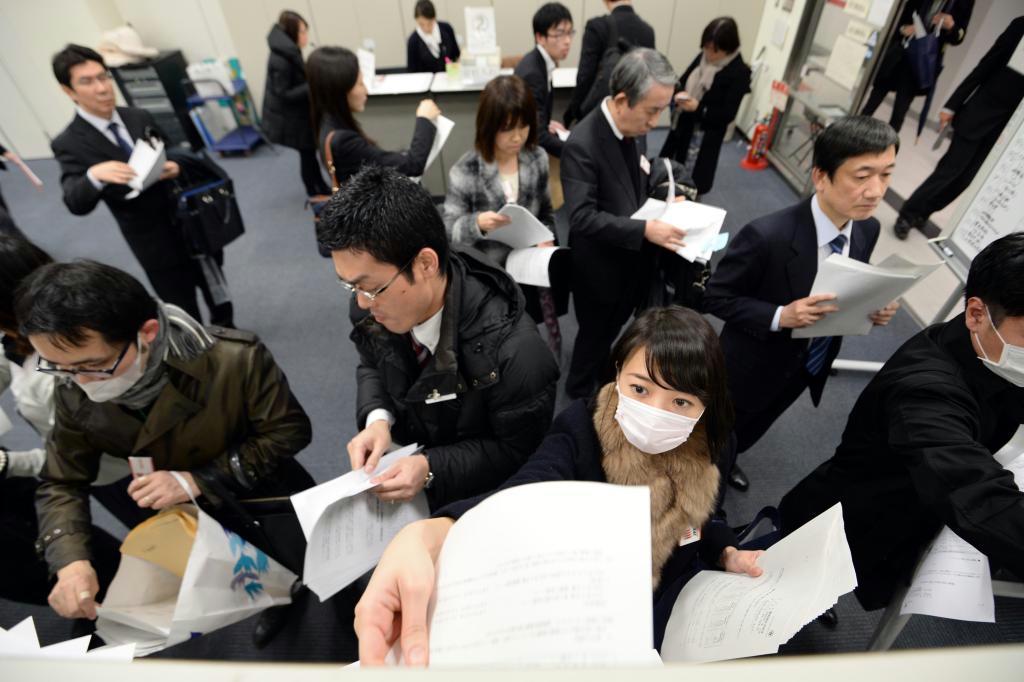 ２０１４年４～１２月期の決算発表がピークを迎え、報道各社の棚に資料を配る企業の担当者ら＝３０日午後、東京都中央区の東京証券取引所