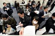 ２０１４年４～１２月期の決算発表がピークを迎え、報道各社の棚に資料を配る企業の担当者ら＝３０日午後、東京都中央区の東京証券取引所