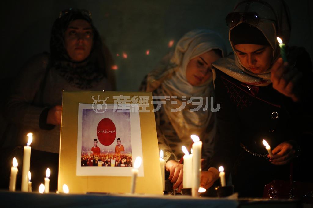 ヨルダンの首都アンマンの日本大使館前で行われた後藤健二さんと湯川遥菜（はるな）さんの産追悼集会で、ろうそくに火をともす人たち＝２０１５年２月２日（ロイター）