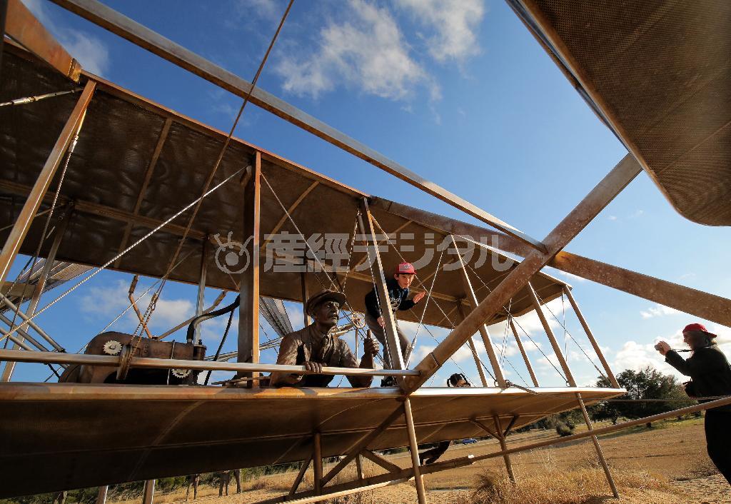 ライト兄弟が人類で初めて飛ばした飛行機「スターフライヤー号」の実物大模型とともに記念写真を撮る観光客。一帯は記念公園となっている＝２０１４年１１月２７日、米ノースカロライナ州東部キティホーク（早坂洋祐撮影）