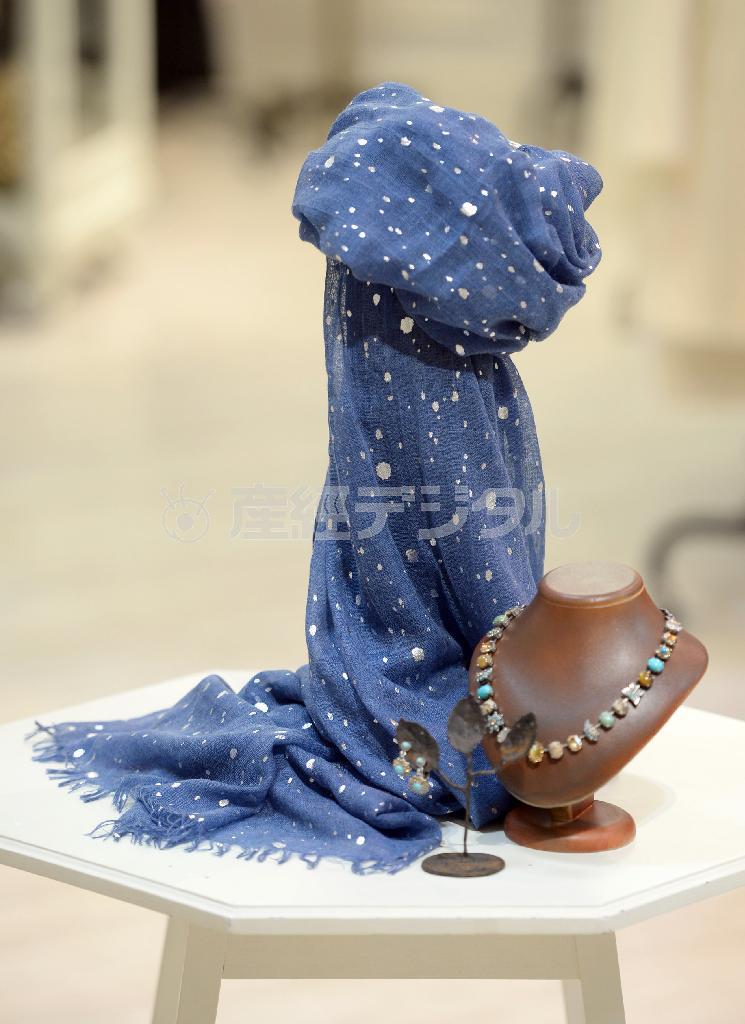 落ち着いたデニムカラーにメタルカラーをプリントをほどこしたストール（左、８５００円）はｅｒｆｕｒｔから。花やチョウ、ターコイズなどの大ぶりのモチーフを使ったネックレス（右、２万５０００円）とイヤリング（中、７８００円）はＡＭＡＲＯから＝２０１５年２月２日、東京都中央区銀座（川口良介撮影）