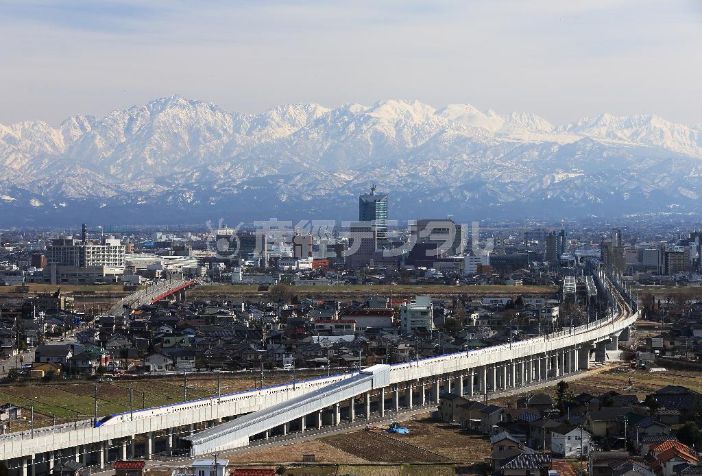 立山連峰を背景にＪＲ富山駅を出発する北陸新幹線の試運転風景。延伸開業で新たな観光資源が脚光を浴びている＝富山市（恵守乾撮影）