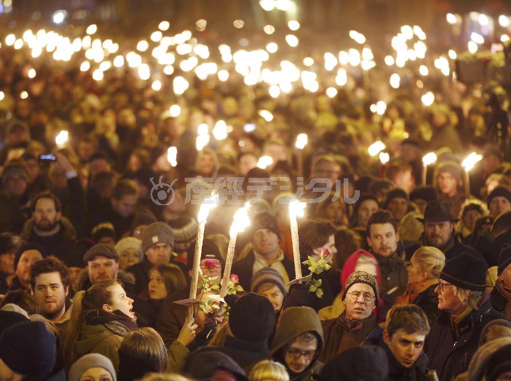 デンマーク・首都コペンハーゲンで行われた連続銃撃テロの追悼式典に参加し、ろうそくをともし冥福を祈る市民ら＝２０１５年２月１６日（ＡＰ）