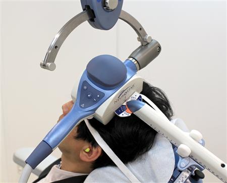 ＴＭＳ治療機器のシートに座って電磁コイルを頭に当てる記者＝東京都新宿区西新宿の新宿メンタルクリニック