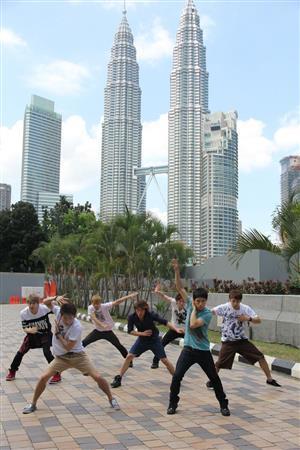 首都クアラルンプールのランドマークにもなっている「ペトロナスツインタワー」をバックに路上でダンスを踊るブルートーキョーのメンバー。ストリートダンスの原点に立ち帰った＝２０１５年２月７日、マレーシア（田中幸美撮影）