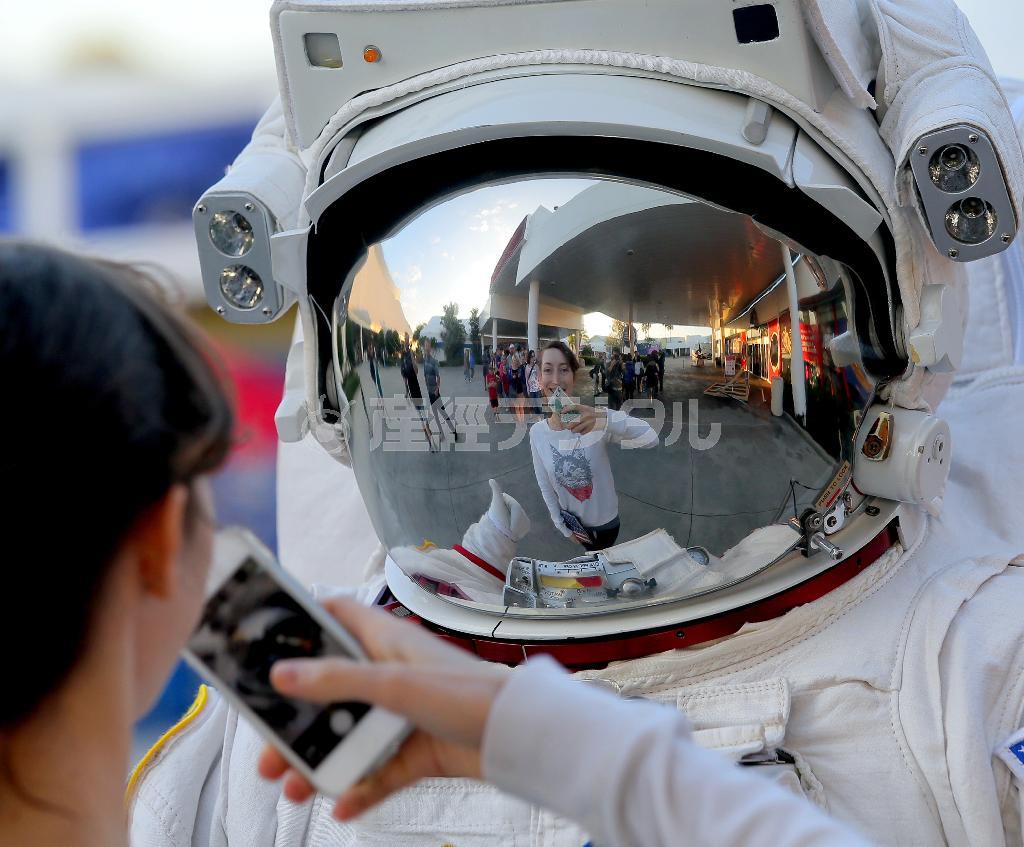 ケネディ宇宙センターの見学者用施設で、宇宙服姿のスタッフと記念写真を撮る観光客＝２０１４年１２月７日、米フロリダ州ケープカナベラル（早坂洋祐撮影）
