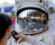 ケネディ宇宙センターの見学者用施設で、宇宙服姿のスタッフと記念写真を撮る観光客＝２０１４年１２月７日、米フロリダ州ケープカナベラル（早坂洋祐撮影）