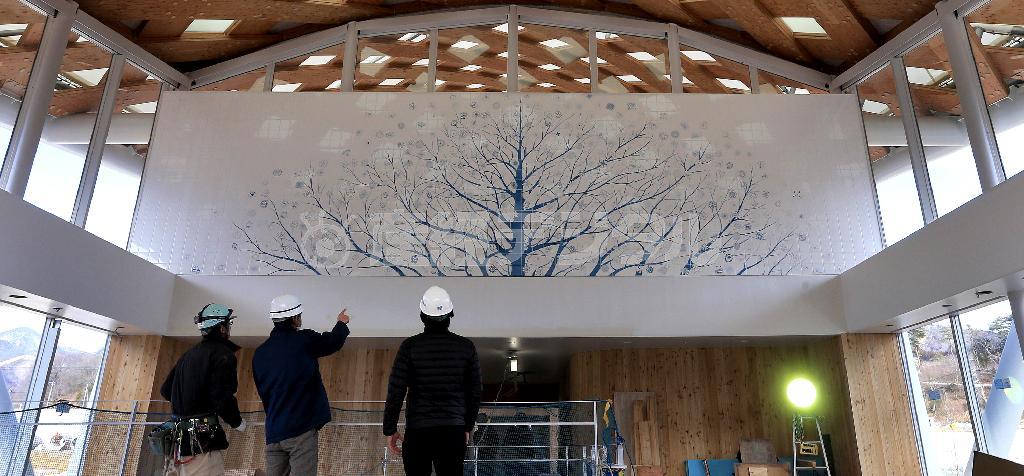 ＪＲ石巻線女川駅駅舎２階の温泉施設「ゆぽっぽ」の待合室に飾られた長さ約１０メートルのタイル絵「家族樹」。大きく枝を広げた木には、公募で選ばれた４５０個の花の絵が組み込まれ、町の復興を静かに見守る＝２０１５年２月３日、宮城県牡鹿郡女川町（鈴木健児撮影）
