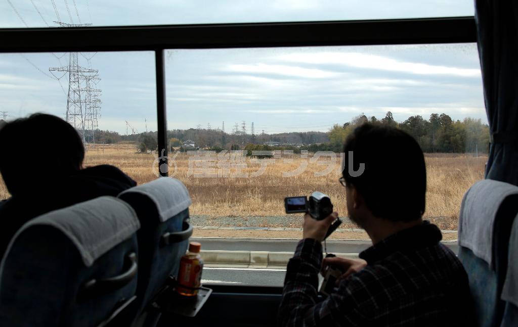 福島第１原発の煙突やクレーンを見つめる乗客＝２０１５年３月１日、福島県双葉郡大熊町（早坂洋祐撮影）