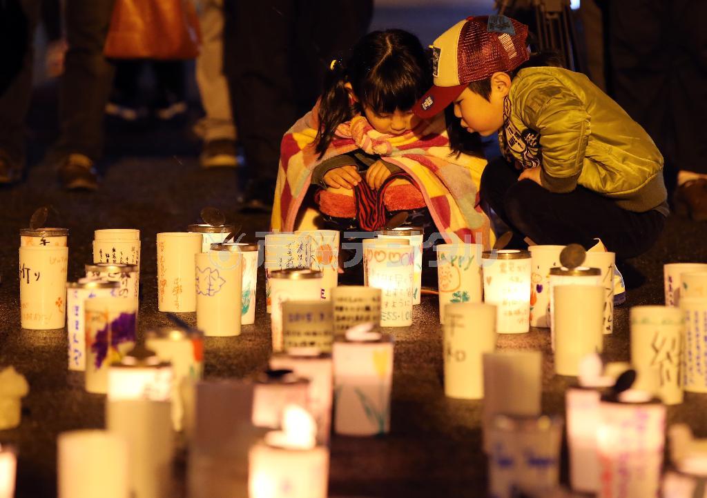 福島県南相馬市で行われた震災犠牲者追悼のキャンドルナイトで、メッセージの書かれたキャンドルを見る子供たち＝２０１５年３月１１日午後（早坂洋祐撮影）