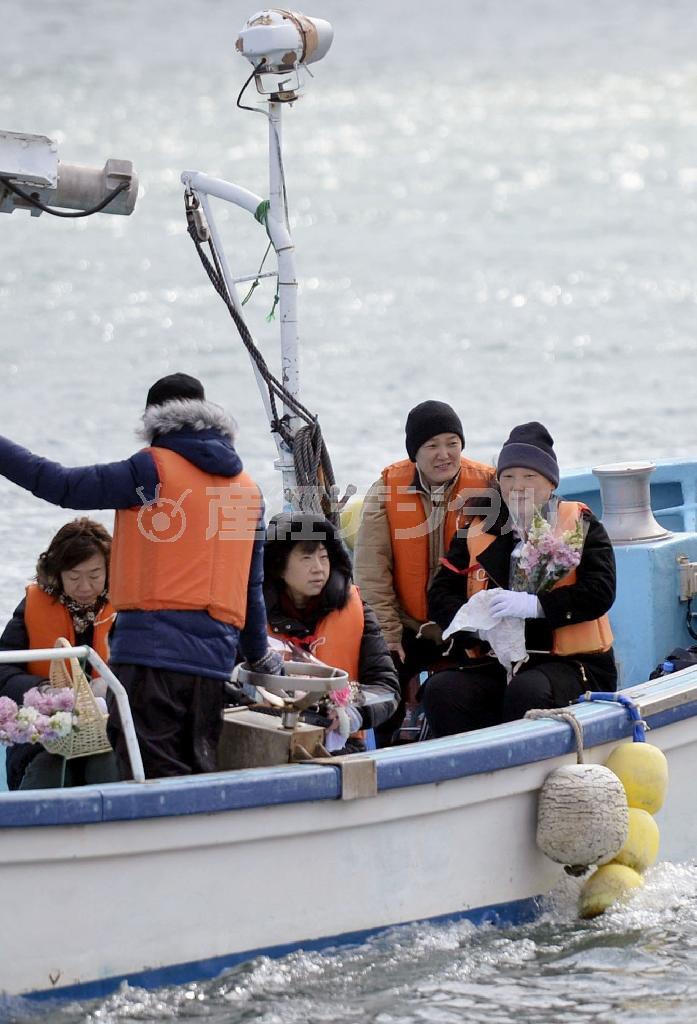 津波の犠牲になった七十七銀行女川支店行員の慰霊のため、花束を抱え漁船で沖へ向かう遺族＝２０１５年３月１１日午前、宮城県牡鹿郡女川町（共同）