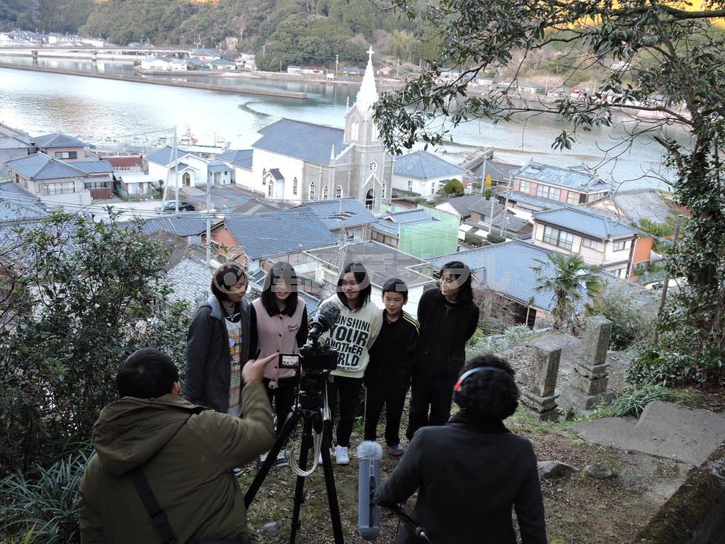 天草のキリシタンの信仰を守ってきた崎津天主堂を背景に、地元の子供たちと家族がハミング、照れながら本番撮影＝２０１５年２月１４日、熊本県天草市（藤沢志穂子撮影）