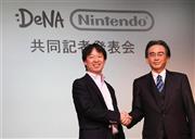 資本業務提携の発表会見で握手するディー・エヌ・エーの守安功社長（左）と任天堂の岩田聡社長＝２０１５年３月１７日、東京都港区（蔵賢斗撮影）