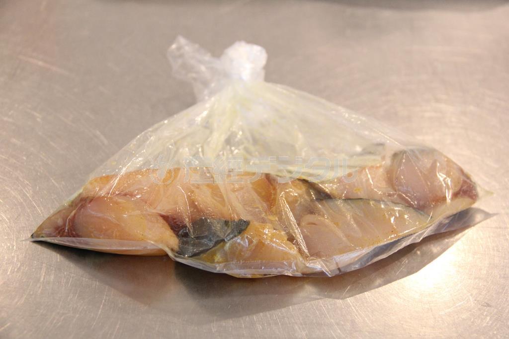 サワラと新じゃがのカレーソテー（作り方１）＿＿サワラをポリ袋に入れ、塩、カレー粉、白ワインを加えて、なじませ、取り出して小麦粉をまぶす。