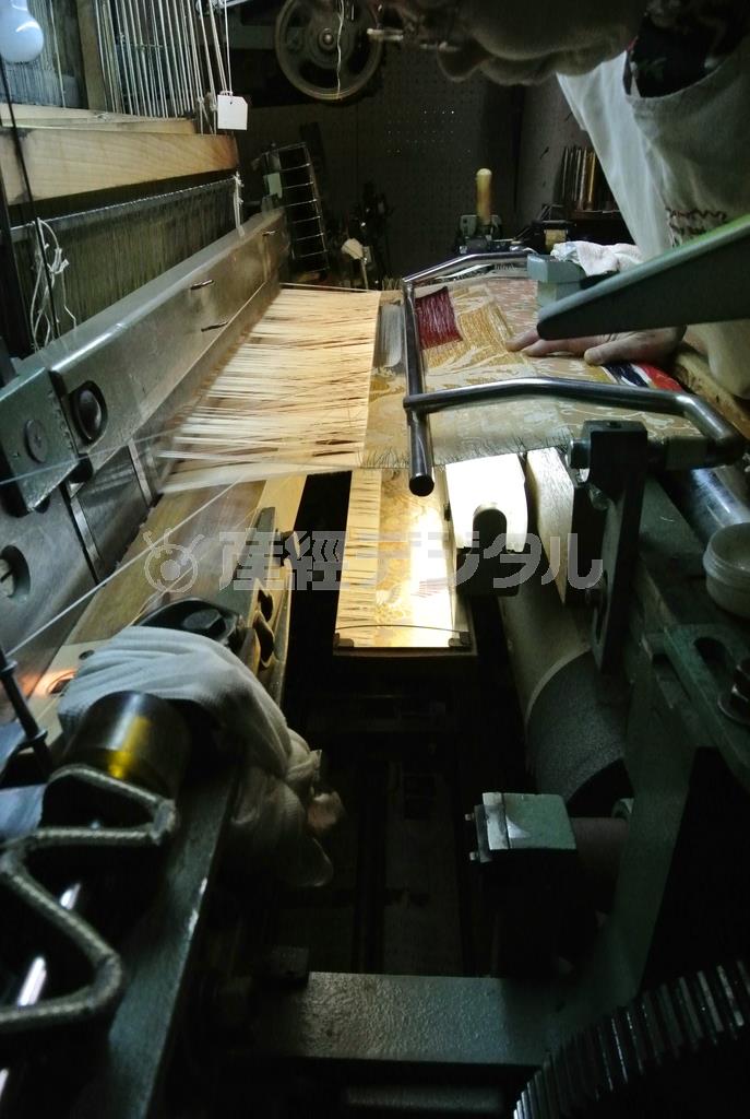 引箔が金襴に織り込まれていく様子。織機に「引箔装置」という専用の装置が付けられており、そこから一本一本織り込まれる＝２０１５年３月１０日（提供写真）