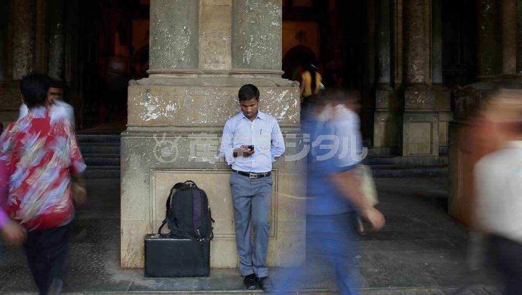 インド西部ムンバイの鉄道駅構内で、スマートフォンを見つめる男性。インド最高裁は、インターネット上で誹謗中傷などをした者に刑事罰を科すことを定めた情報技術法の条項は違憲との判決を下した＝２０１５年３月２４日（ＡＰ）