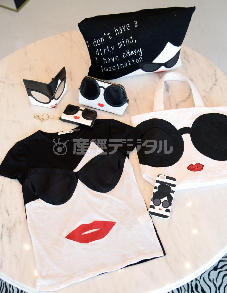 デザイナーのステイシー本人をイメージしたグッズの数々。下段は左がサングラスが印象的な表参道店限定Ｔシャツ（１万８０００円）、ｉＰｈｏｎｅケース（手前、６０００円）、表参道店１周年を記念したトートバッグ（右、１万４０００円）。上段は右から表参道店限定クッション（９５００円）、コスメティックバッグ（１万２０００円）、財布（１万６０００円）、表参道店限定パスポートケース（６０００円）＝２０１５年３月１２日、東京都渋谷区（川口良介撮影）