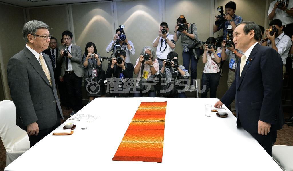 初会談で厳しく応酬した沖縄県の翁長雄志（おなが・たけし）知事（左）と菅義偉（すが・よしひで）官房長官＝２０１５年１０月５日午前、沖縄県那覇市内のホテル（共同）