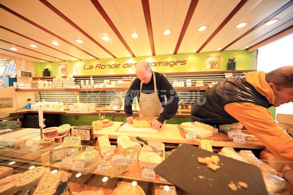 さすがフランス、チーズがたくさん売られています。ほとんどが量り売りで、このように店員さんにカットしてもらいます。チーズの名前や値段がはっきり写っている方が情報量が多く、見る人を楽しませることができます。その点を考えながら露出決定すると良いでしょう＝２０１５年３月８日（須藤夕子さん撮影）