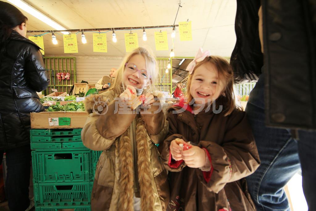 毎週このマルシェに家族でやってくるという姉妹です。日本から持って行った金魚のオモチャを渡したらとても喜んで、この笑顔を向けてくれました。子供は背が低いので市場の中では埋もれて撮りにくくいので、望遠レンズは不向きです。なるべく広い画角で撮れるズームレンズが良いでしょう。これは１１ミリ～２４ミリのズームレンズで撮影しました＝２０１５年３月８日、フランス（須藤夕子さん撮影）