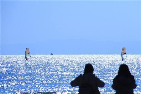【読者写真（今回の読者：神奈川県鎌倉市、小田扶抄江さん）】きらめく海を背景に、カップルの微妙な距離感が「爽やかさ」を生み出しています。シャッタースピードを早くしているので、ウィンドサーフィンの帆がまったくブレていません。アドバイスをするならば、カップルのお尻くらいまで人物を入れた方が落ち着く構図になるかと思います（提供写真）