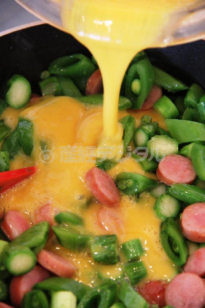 春野菜のスパニッシュオムレツ（作り方２）＿＿フライパンにオリーブ油を熱し、ソーセージを炒め、アスパラガス、スナップえんどうを加える。さっと炒めたら（作り方１：卵をわりほぐし、塩、こしょうを加え混ぜる）を回し入れて半熟状になるまで大きくかき混ぜる。