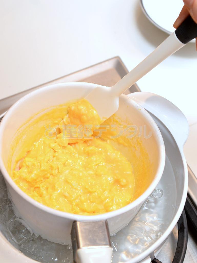 ホテルのスクランブルエッグ＿＿（作り方３）バターの溶けた鍋に加え、湯煎で少し固まったところから混ぜながらトロットロに仕上げる。好みで塩をかけてトーストパンに載せていただく（宮崎瑞穂撮影）