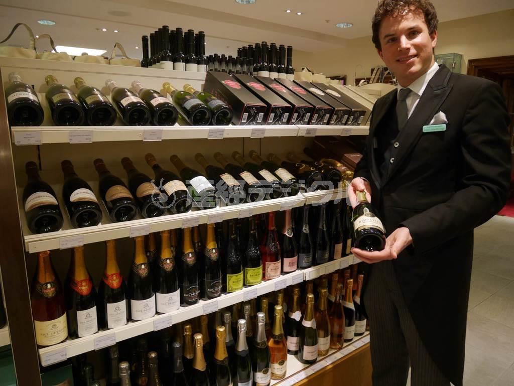 首都ロンドンの老舗百貨店フォートナム＆メイソンのワインコーナーで、英国産のスパークリングワインを手に取ってみせる店員＝２０１５年４月８日、英国（内藤泰朗撮影）