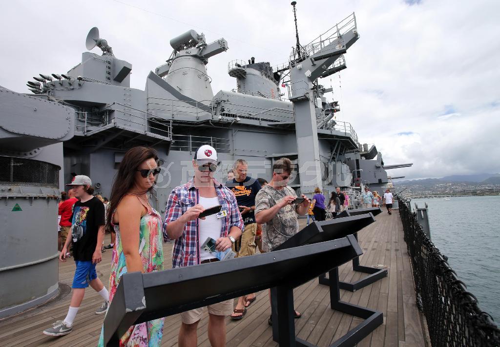 ハワイ・オアフ島の真珠湾の戦艦ミズーリで鹿児島県沖で特攻機が突入した戦艦ミズーリの右舷デッキの説明板を読む来場者＝２０１５年４月１１日、米ハワイ州（鈴木健児撮影）