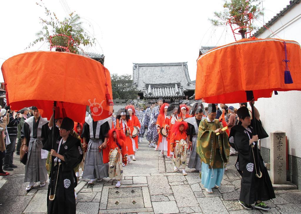 光念寺を出発する今宮やすらい会の青組（右）と赤組の行列。花笠から垂れる房の色が組をあらわす＝２０１５年４月１２日午後、京都市北区（田中幸美撮影）