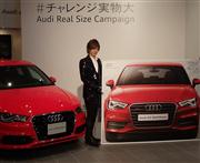 アウディ「Ａ３スポーツバッグ」の実車（左）と世界最大の新聞折り込み広告の間でポーズを決めるＤＡＩＧＯさん＝１６日、東京都渋谷区のアウディフォーラム東京