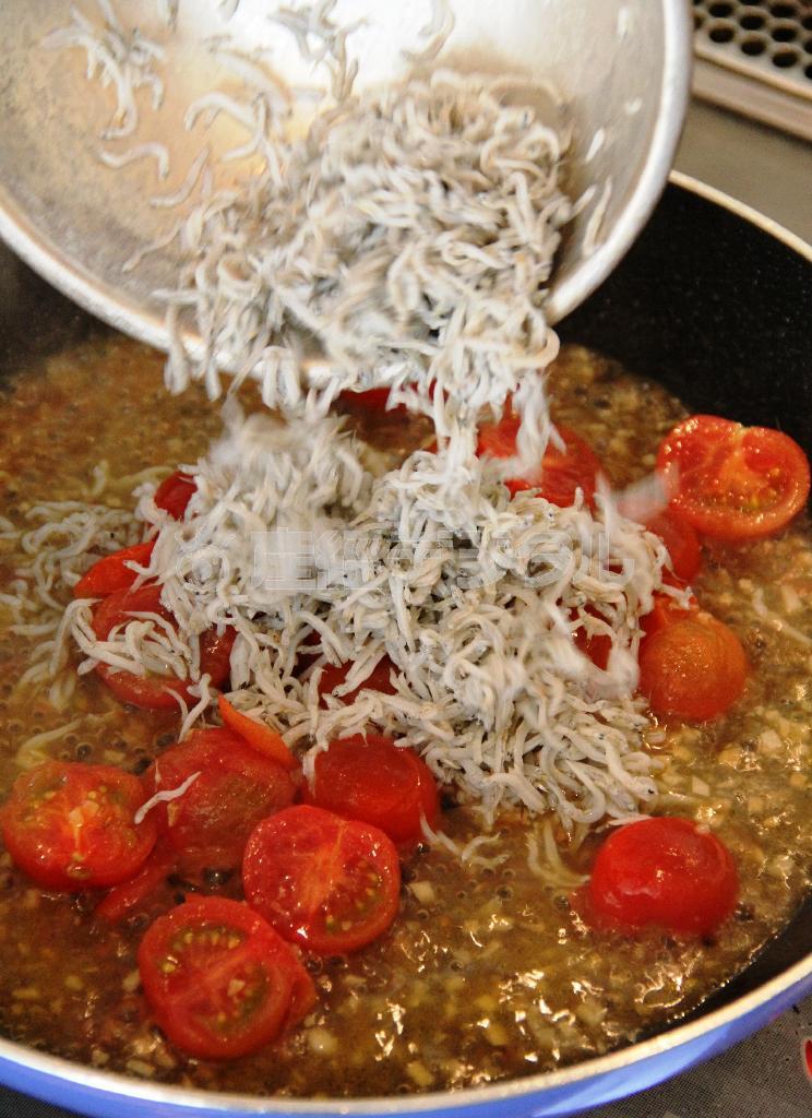 しらすとカブの葉のパスタ（作り方２）＿＿オリーブ油、にんにく、唐辛子を弱火にかけ、にんにくが色づいたら、唐辛子を取り出す。ミニトマトとお玉２杯分のゆで汁を加え、トマトが崩れてきたら、しらす干しを加え、さっと混ぜる。