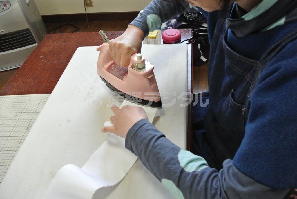 雪花絞りのためにアイロンで生地を丁寧に折りたたむ田端和樹さんの奥さん。夫婦の共同作業で作り上げている＝２０１５年３月２４日（提供写真）