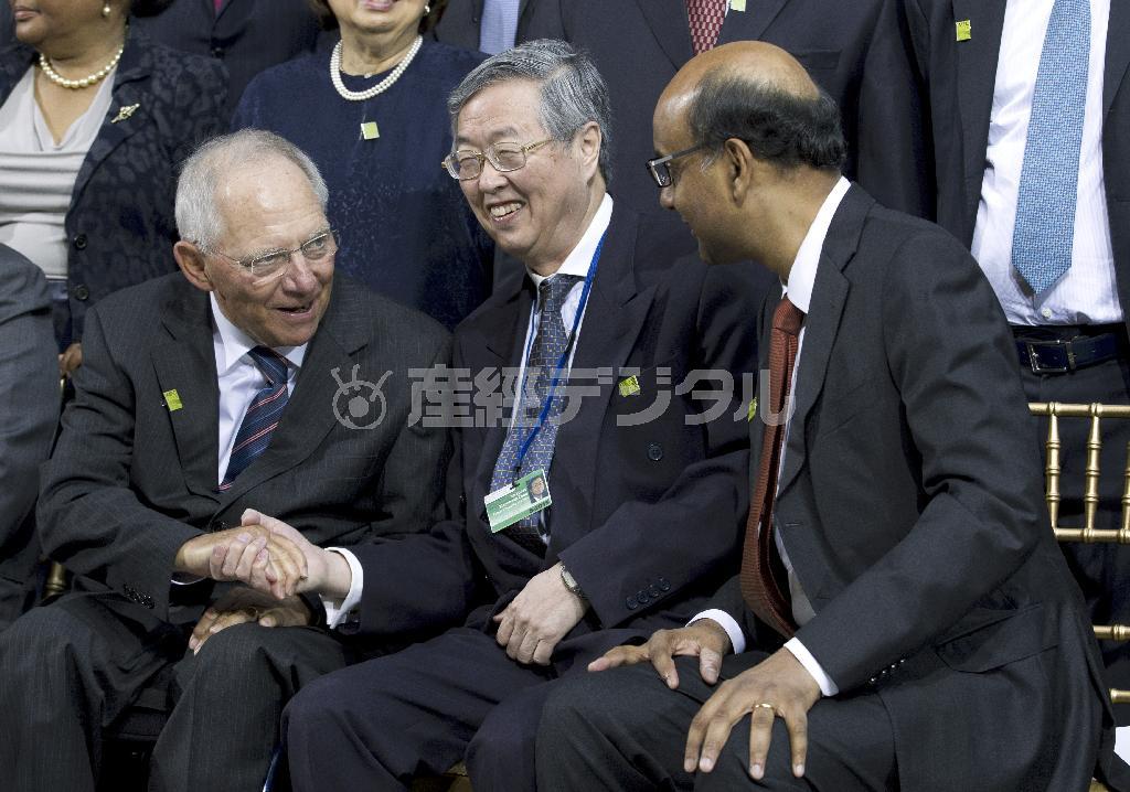 国際通貨基金（ＩＭＦ）・世界銀行合同開発委員会にあわせた記念撮影で、ドイツのウォルフガング・ショイブレ財務相（左）とシンガポールのターマン・シャムガラトナム財務相（右）に挟まれ、満面の笑みを浮かべる中国人民銀行の周小川総裁（中央）＝２０１５年４月１８日、米国・首都ワシントン（ＡＰ）