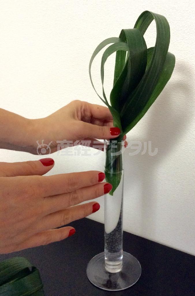 （手順２）つる首のガラスの花器に水を入れ、加工したハランを２枚を動きがでる角度でいれる＝２０１５年４月２０日（花千代さん提供）