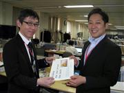 育児への支援を約束する「おめでとうカード」を今井勇太・個人商品業務部副長（写真右）に手渡す仁田一郎・個人商品業務部課長（写真左）＝２８日、東京都新宿区の損害保険ジャパン日本興亜本社