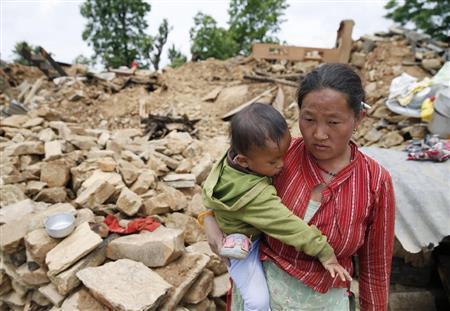 地震で多くの建物が倒壊したネパール北東部のシンドパルチョーク地区で、子供を抱きうつむく女性＝２０１５年４月３０日（共同）