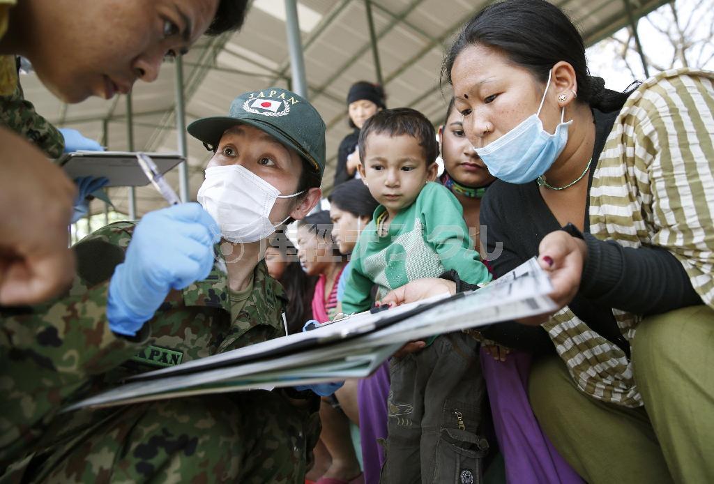 カトマンズの避難所で、単語帳を使って体調不良を訴える人たちを診察する自衛隊の医療援助隊員＝２日（共同）