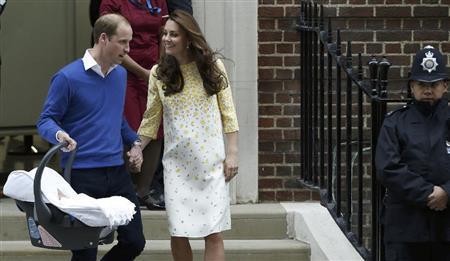 第２子の女の子をチャイルドシートに入れて運ぶウィリアム王子（右）と、しっかり手をにぎるキャサリン妃。ウィリアム王子は、第１子のジョージ王子のときと同じように自ら自動車の後部座席にシートをセットし、自分で運転して退院していった＝２０１５年５月２日、英国・首都ロンドン（ＡＰ）