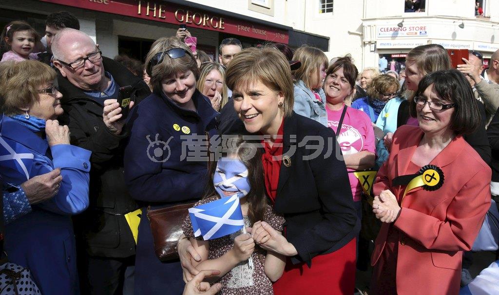 終盤を迎えた英総選挙で、少女と記念撮影に応じるスコットランド民族党（ＳＮＰ）のニコラ・スタージョン党首（中央）。ＳＮＰは急速に支持を広げ、総選挙後の政権枠組みを左右する可能性もでてきている＝２０１５年５月４日、英スコットランド西部ラーグス（ロイター）