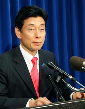 ４日、ワシントンで記者会見する西村康稔内閣府副大臣（共同）