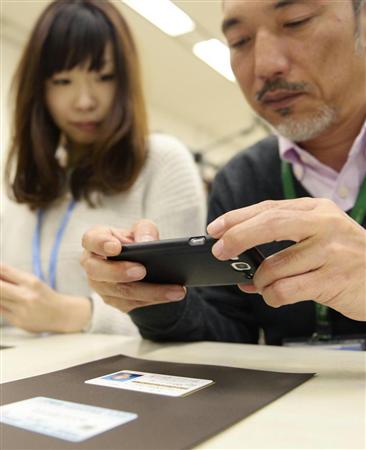 ＮＴＴデータが行った実証実験。参加者が健康保険証についている社員番号を個人番号に見立て、スマートフォンで読み取った＝３月１０日、東京都江東区