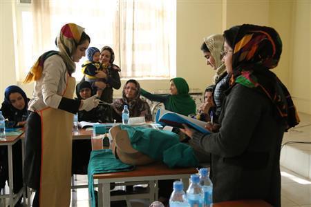 保健・医療従事者の養成プログラムで、模型を使って分娩の方法について学ぶ女性たち＝２０１４年１１月１６日、アフガニスタン・ヘラート州（ワールド・ビジョン・ジャパン撮影）