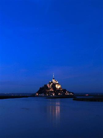 （１９：００）みるみるうちに潮が満ちてきて、日没の午後７時が近づくと修道院に明かりがともり始め、水面にもう一つのモンサンミッシェルが映し出されました。撮影した時は、展望デッキの真横（左側）に太陽が落ちましたが、これからの時期や夏に撮影に行けば、修道院の後ろの方に太陽が落ちるので、グラデーションがさらに美しい写真が撮れるはずです。シルエット写真も撮ることができます＝２０１５年３月６日、フランス・モンサンミッシェル（須藤夕子さん撮影）