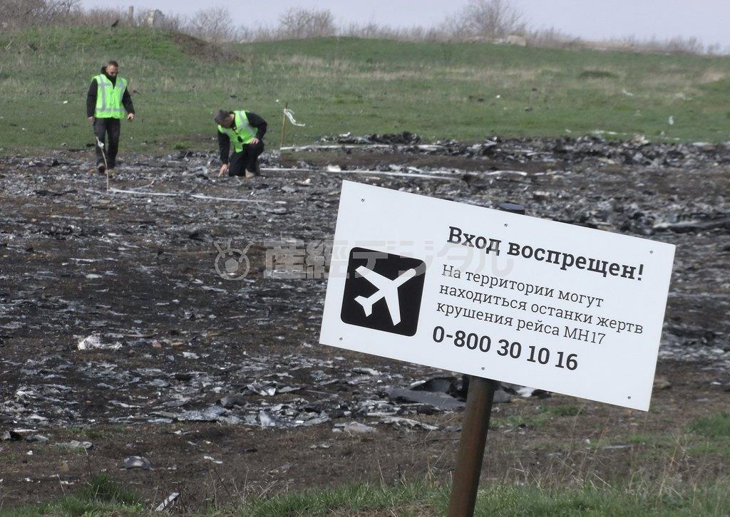 ウクライナ東部ドネツク州のマレーシア機墜落現場で残骸などを調べる調査官。手前には「立ち入り禁止」の看板が立つ。今秋の最終報告書発表を前に真相をめぐる議論が活発化している＝２０１５年４月１６日（ロイター）